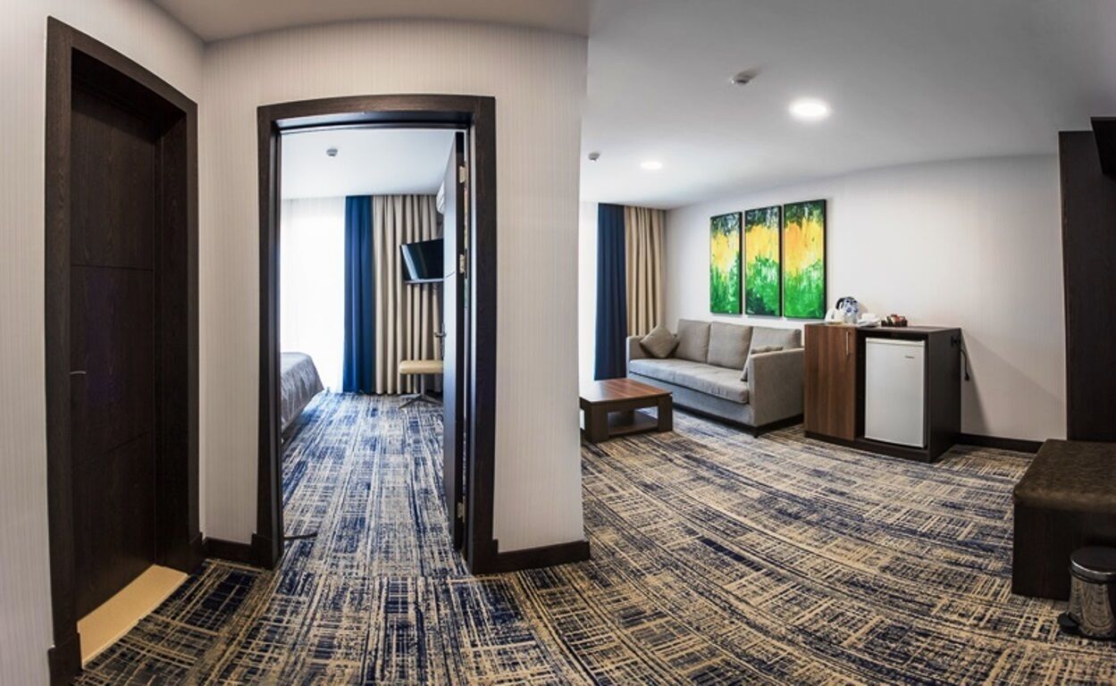 A hotel room with a patterned carpet, a sofa, a small table, and a cabinet.