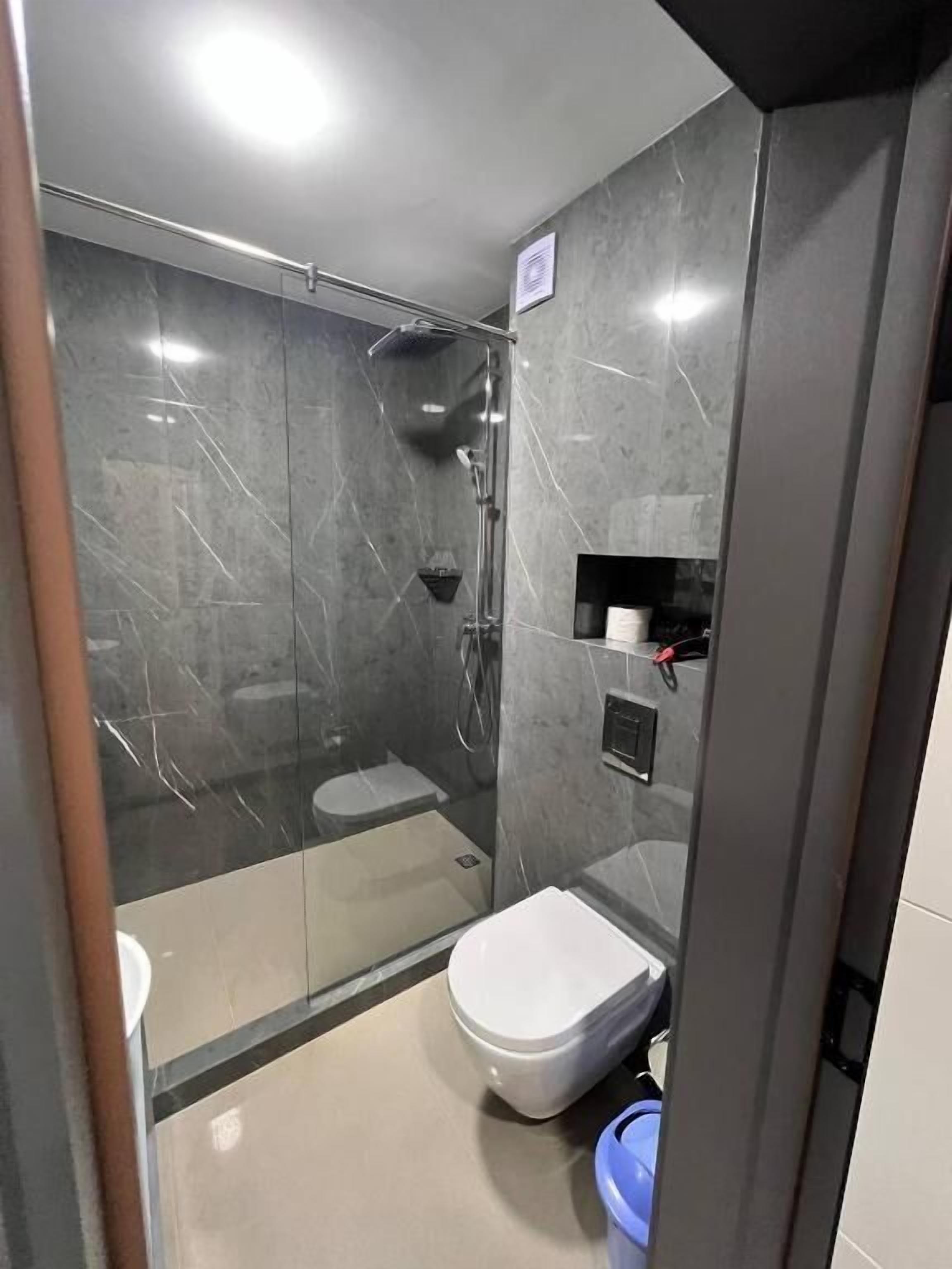 Um banheiro moderno com chuveiro de vidro, vaso sanitário e pia.