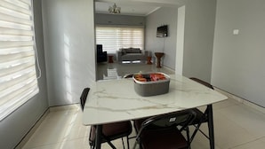A dining area with a marble table, chairs, and a basket of snacks.