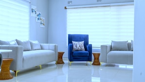 A modern living room with two sofas, a blue armchair, and a coffee table.