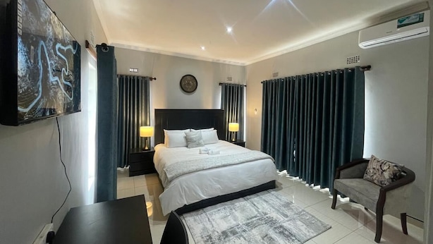 A modern hotel room with a large bed, bedside lamps, a desk, and a TV on the wall.