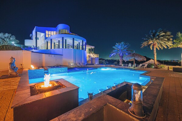 Une maison moderne dotée d’une piscine, d’un espace salon extérieur et d’un patio bien éclairé.