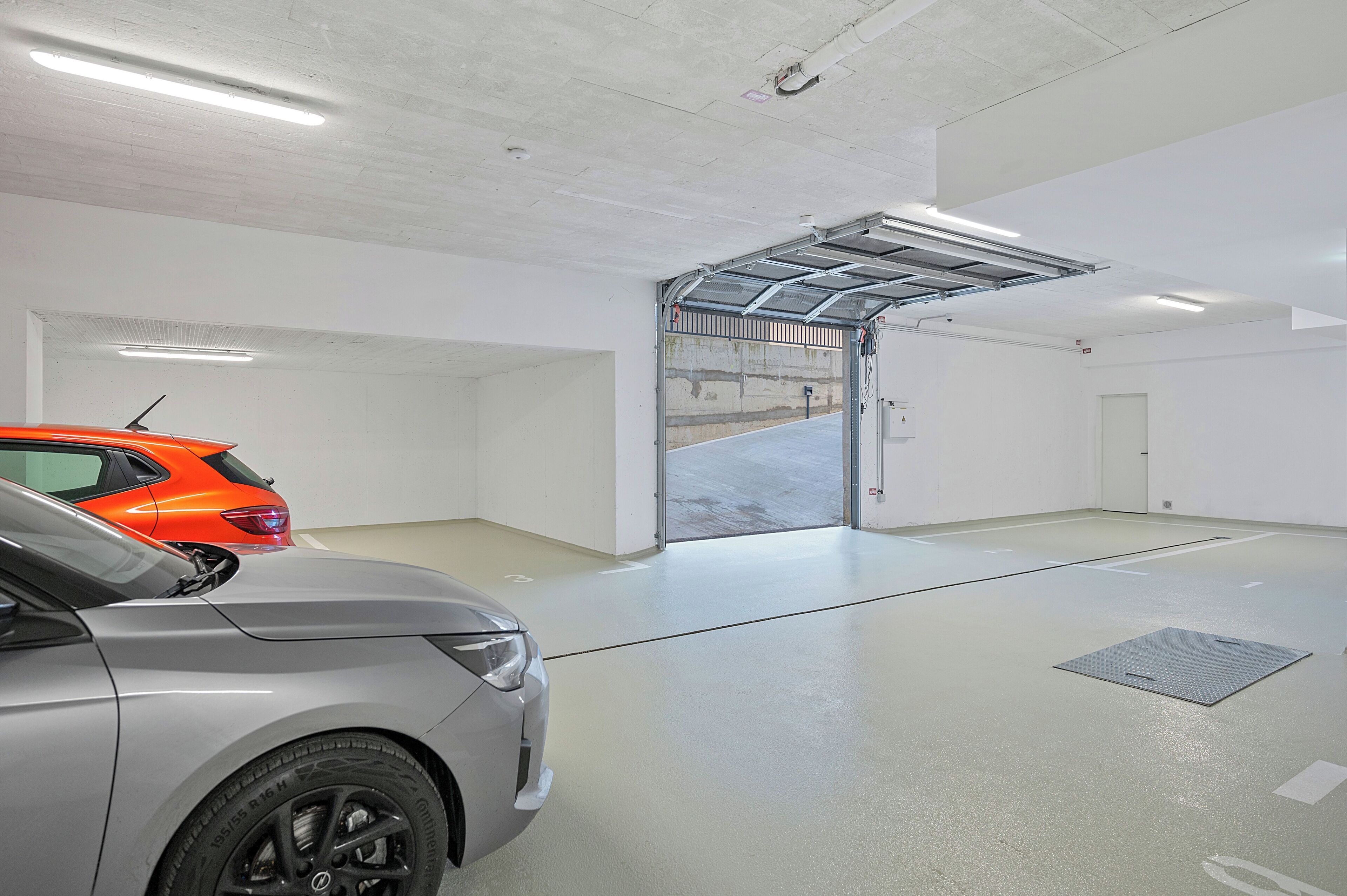 Un garage pouvant accueillir deux voitures, avec une porte de garage et un intérieur propre et blanc.