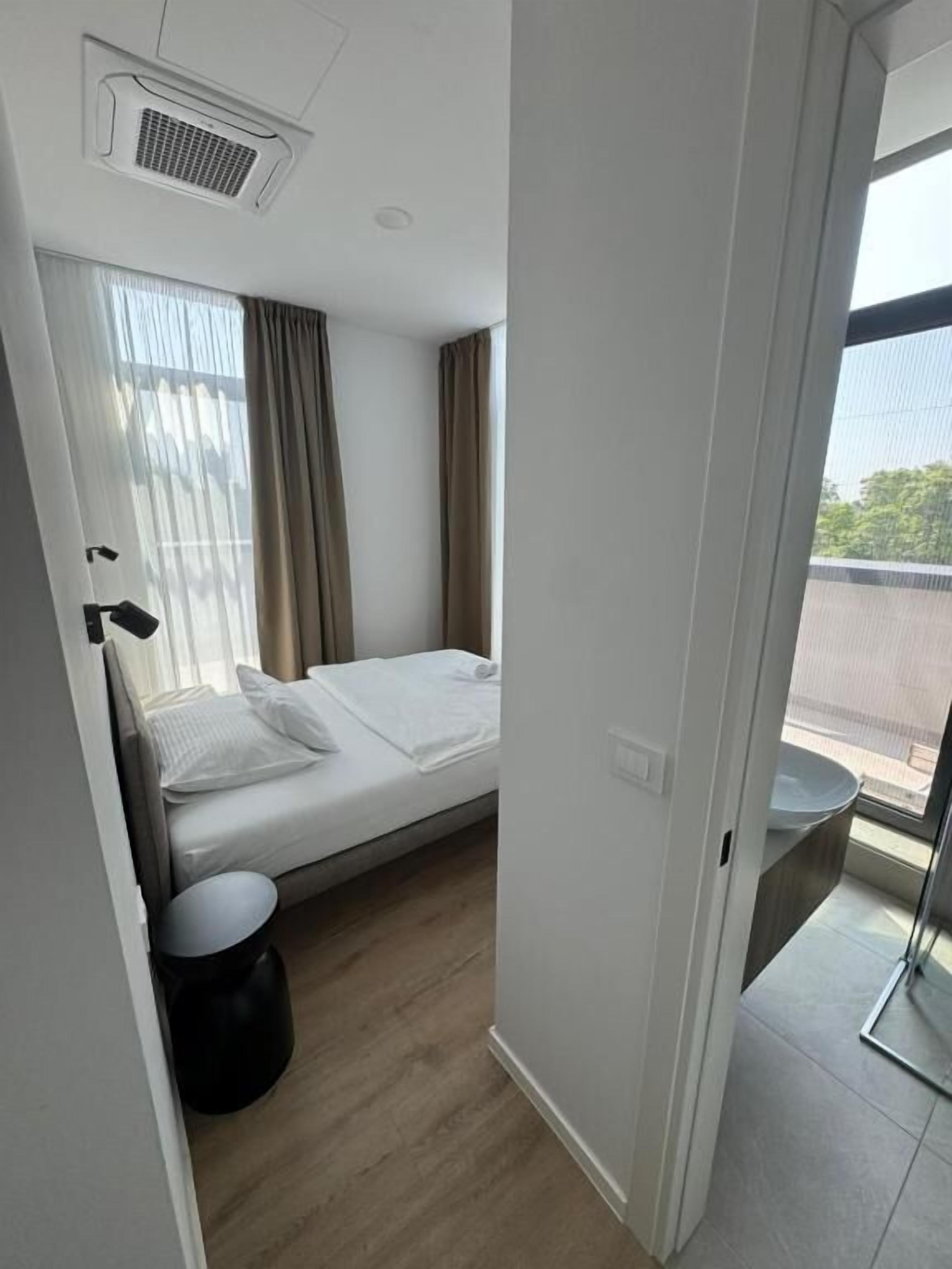 Un dormitorio moderno con cama, una mesita redonda y un ventanal con cortinas.