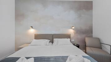 A modern hotel room with a large bed, two bedside tables, and a chair.