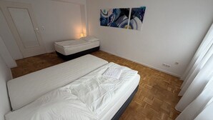A bedroom with a double bed, a bedside table, a wall-mounted artwork, and a door.