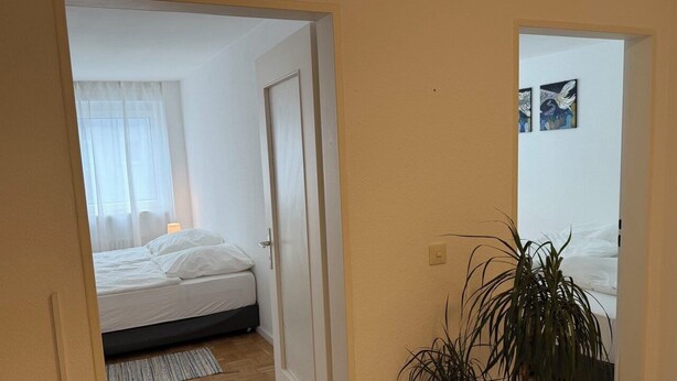 A bedroom with a bed, a bedside table, and a potted plant.