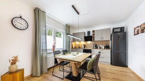 Cozinha moderna com área de refeições, piso de madeira e um relógio na parede.