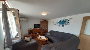 Ein Wohnzimmer mit einer Couch, einem kleinen Tisch, einem Schrank und einem Fernseher.