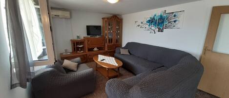 A living room with a sofa, a small table, a cabinet, and a television.