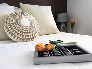 A neatly made bed with a geometric-patterned pillow, a tray with chocolates, and a bouquet of tulips. - Villa Reina in Vinišće (Vinišće)
