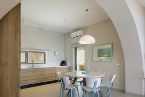 A modern kitchen with a round dining table, white chairs, and a pendant light. - Melampes Villa, Seaview Escape, Heated Pool & Spa (Rethymno)