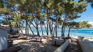Un espace aménagé au bord de la plage, avec un sol en pierre, des bancs et une vue sur la mer.