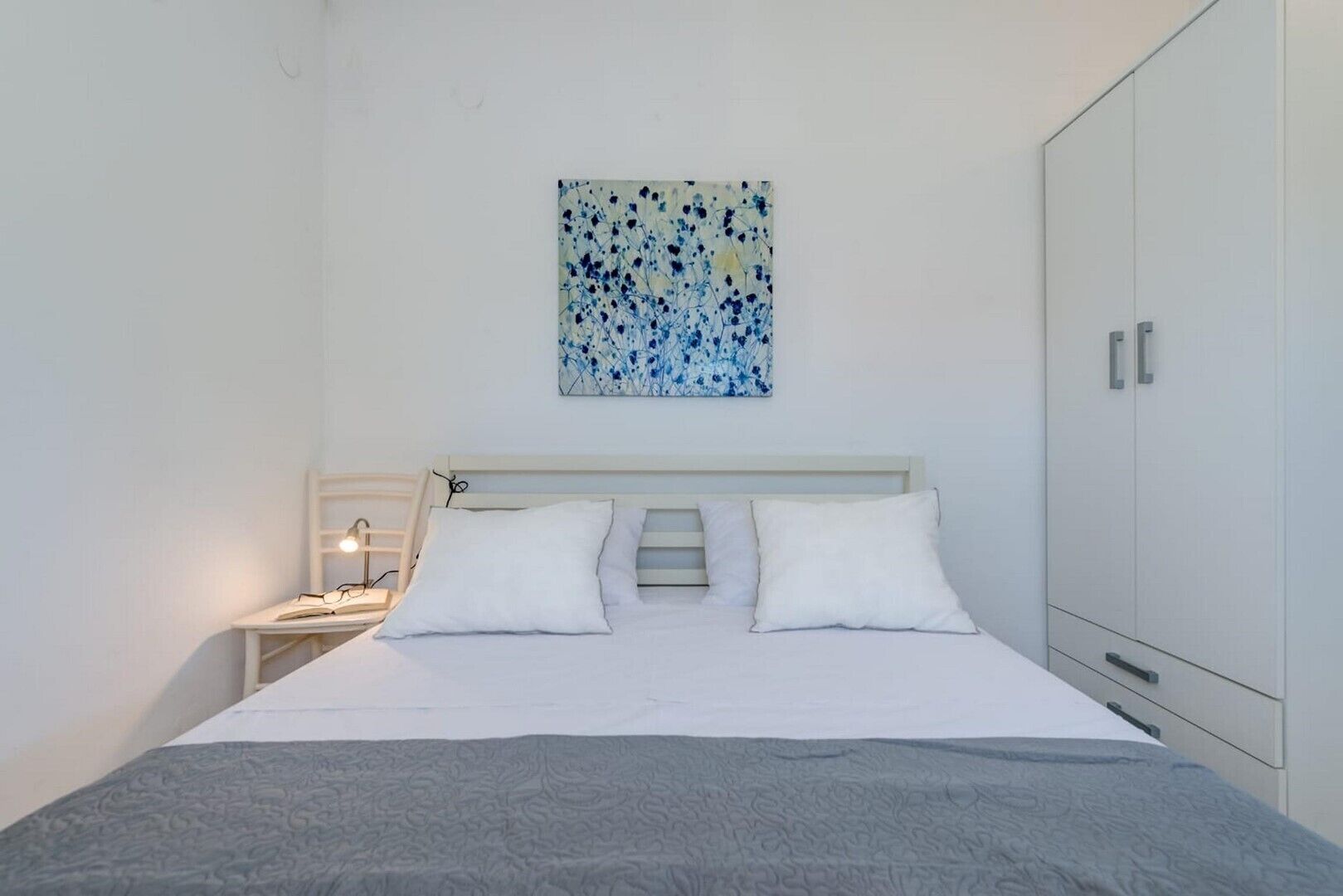 A bedroom with a bed, bedside table, lamp, and wardrobe.