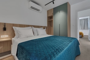 A modern bedroom with a bed, white bedding, a teal quilted bedspread, a wooden headboard, a wardrobe, and an air conditioning unit. - Superior 3BR Villa Vista Divina w/ Pool (Zavala)