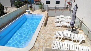 A rooftop pool with clear blue water, surrounded by stone flooring and white lounge chairs. - Two Bedroom Apartment with Shared Pool (Arbanija)