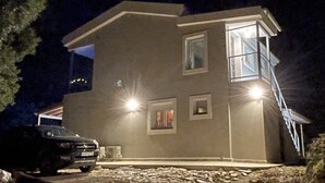 Een twee verdiepingen tellend huis met garage, oprit en een auto ervoor geparkeerd.