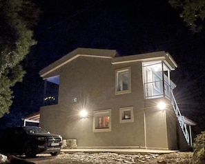 A two-story house with a garage, a driveway, and a car parked in front. - Sea panoramic view apartment 2nd floor of a villa 15 min walk to the beach (Corfou)