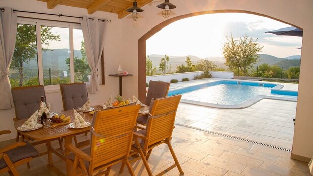 Un espace repas avec vue sur une piscine et des montagnes.