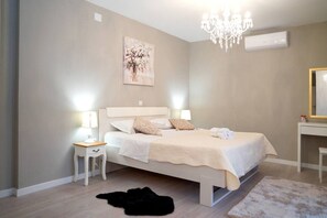 A bedroom with a bed, bedside tables, a chandelier, a painting, and a mirror. - Four Bedroom Villa with Pool (Lećevica)