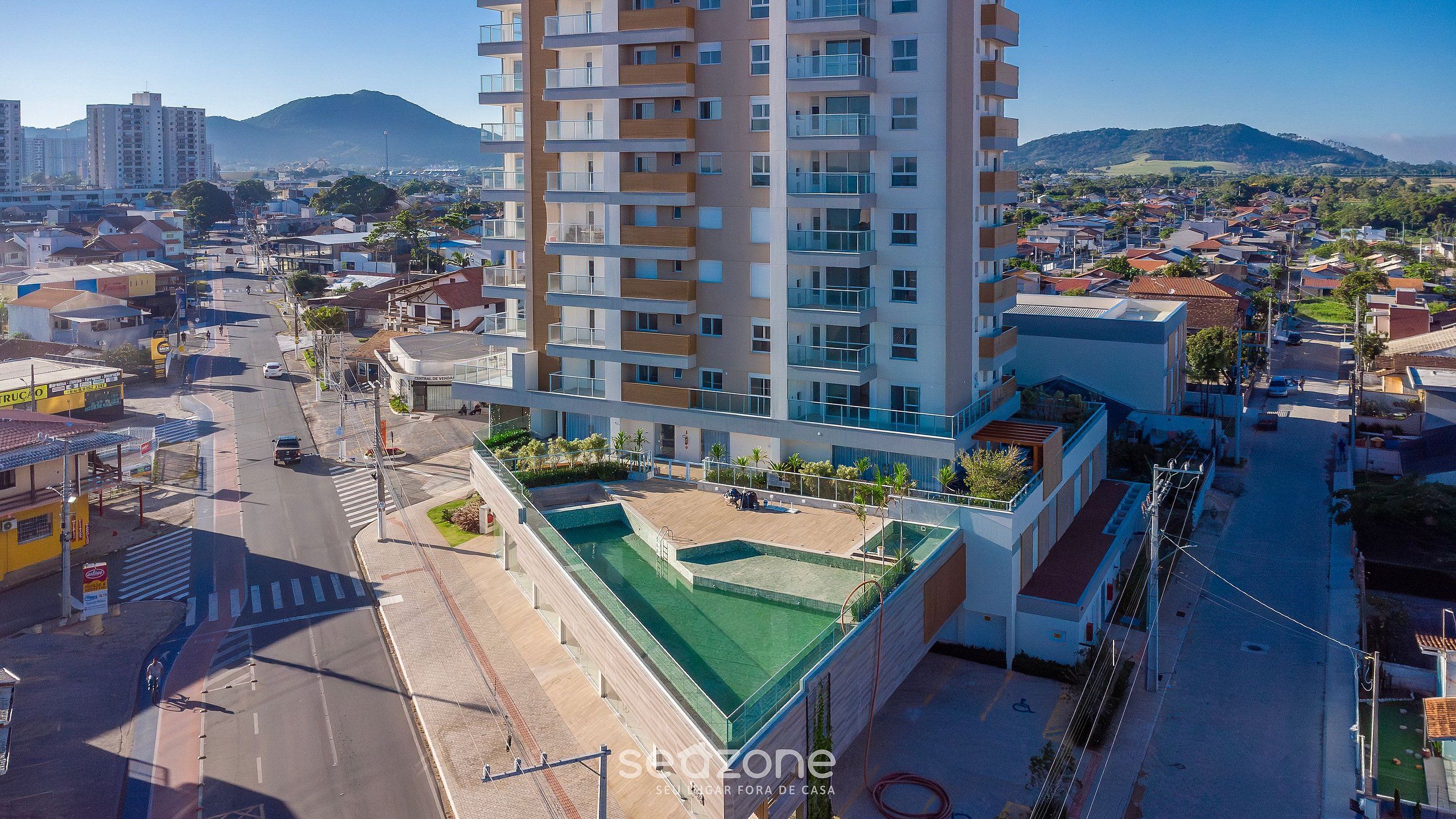 Ein Hochhaus mit Pool auf dem Dach und Blick auf die umliegende Stadtlandschaft.