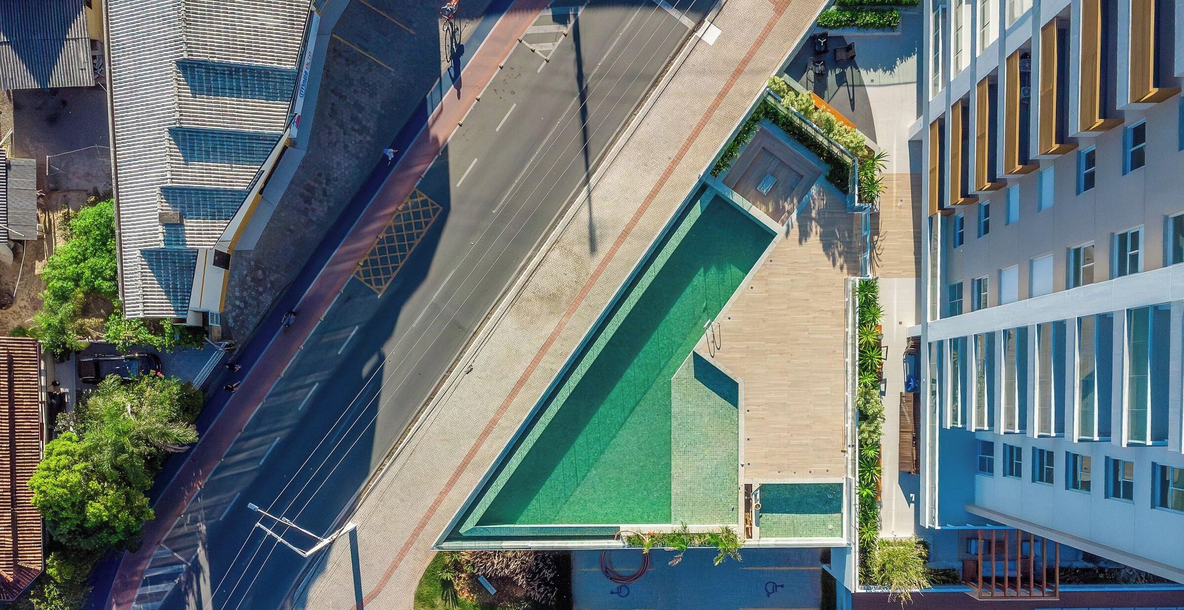 Vista aérea de un edificio moderno con un área de techo verde, al lado de una calle con carril bici.
