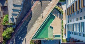 An aerial view of a modern building with a green rooftop area, adjacent to a road with a bicycle lane. - Apt in Condo w/ Pool and Sea View - Bhc1206 (Penha)