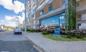 A modern building with a glass facade, a sign for 'BERSI homeclub,' and a paved sidewalk. - Apt in Condo w/ Pool and Sea View - Bhc1206 (Penha)