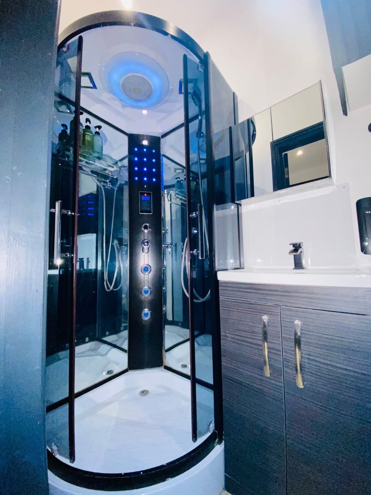 A modern bathroom with a glass-enclosed shower stall, a vanity with a mirror, and a sink.