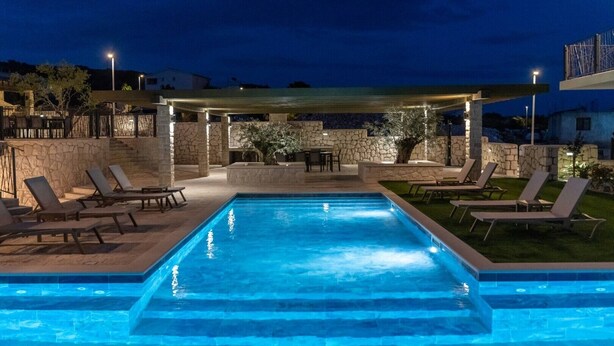Una piscina amb gandules i una zona d'estar coberta de nit.
