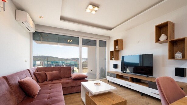 Una sala de estar moderna con un ventanal grande, un televisor de pantalla plana y una mesa de centro de madera.