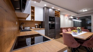 Una cocina moderna con estufa integrada, refrigerador y comedor con mesa y sillas.