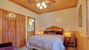 A bedroom with a wooden ceiling, a bed with floral bedding, a nightstand, and a wooden wardrobe. - Woodsy Alton Couple's Retreat Near Bryce Canyon (Duck Creek Village)