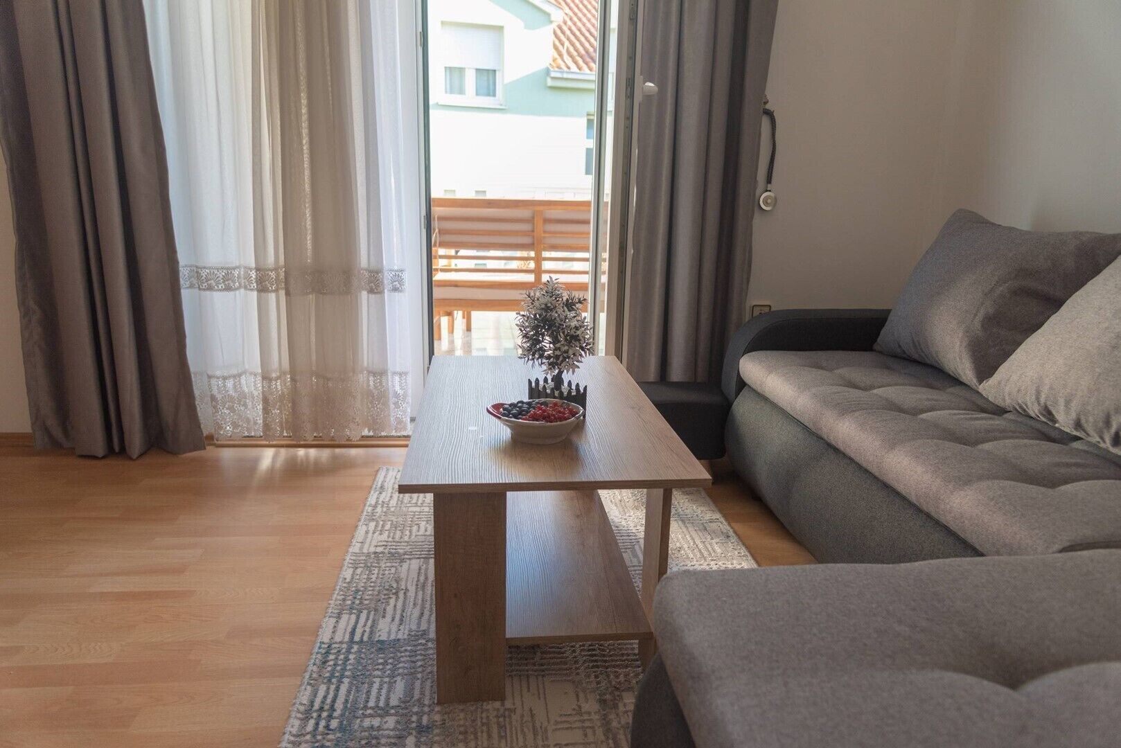 En moderne stue med et træsofabord, en grå sofa og en lille dekorativ plante.