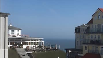 A coastal building with a balcony overlooking the sea, a sign indicating a restaurant, and a clear sky.
