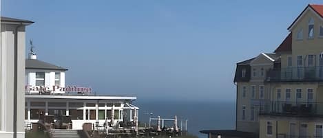 En byggnad vid kusten med en balkong som vetter mot havet, en skylt som visar att det är en restaurang, och en klar himmel.