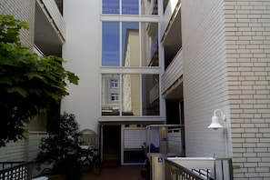 Un edificio de varios niveles con una escalera central, una bicicleta y una rampa accesible para sillas de ruedas.