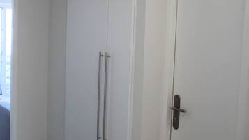 En hvid dør med sort håndtag og en lodret metalstang.