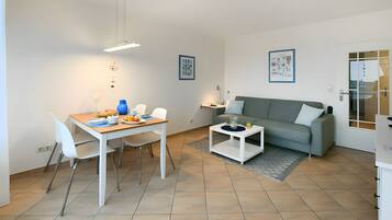 A modern living room with a dining area, a grey sofa, and a coffee table.