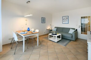 Un salon moderne avec un coin repas, un canapé gris et une table basse.