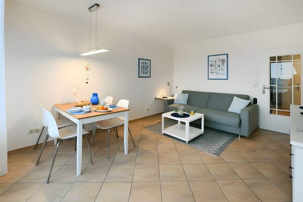Una sala de estar moderna con comedor, un sofá gris y una mesa de centro.