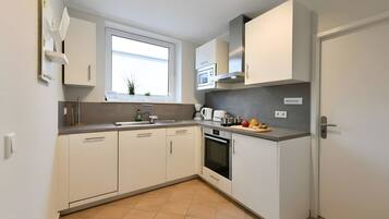 A modern kitchen with white cabinets, a built-in oven, and a window above the sink.