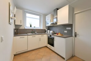 A modern kitchen with white cabinets, a built-in oven, and a window above the sink.