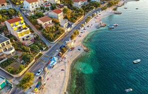 An aerial view of a coastal town with a beach, clear blue waters, and boats. - Studio Apartment Close to Beach (Mastrinka)