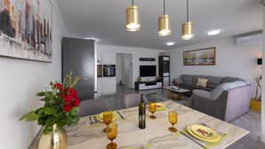 Una sala de estar moderna con un sofá gris, una mesa de comedor con platos amarillos y copas de vino, y un cuadro en la pared.