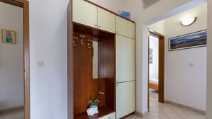 Ein Flur mit einem Kleiderschrank, einer Topfpflanze und einem Bild an der Wand.