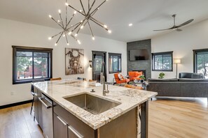 A modern kitchen with a large island, built-in appliances, and a dining area with a gray sofa and orange chairs. - Hike & Unwind, Stylish Wooded Retreat in Piedmont! (Piedmont)