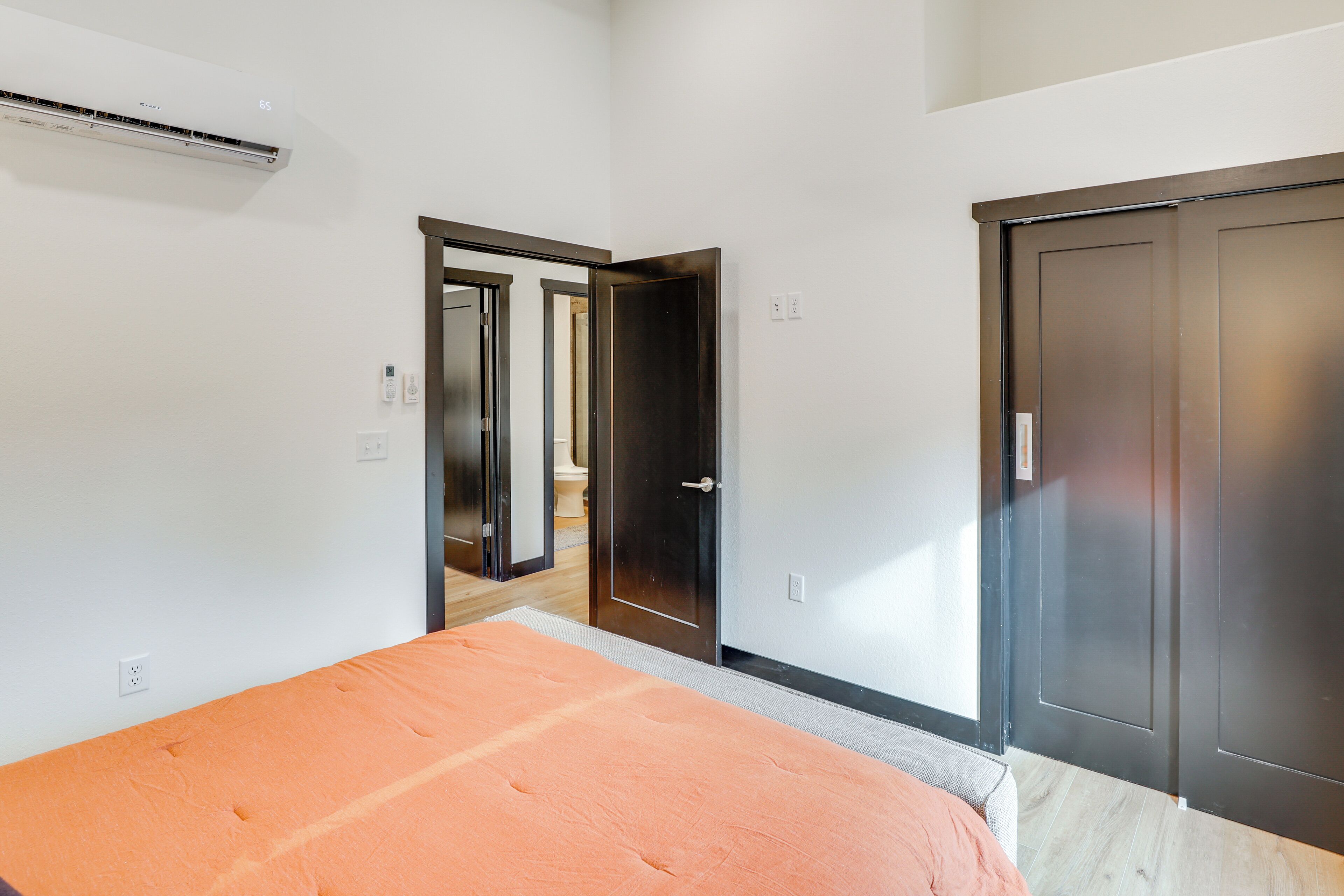 A bedroom with a bed, a wardrobe, and an air conditioning unit.