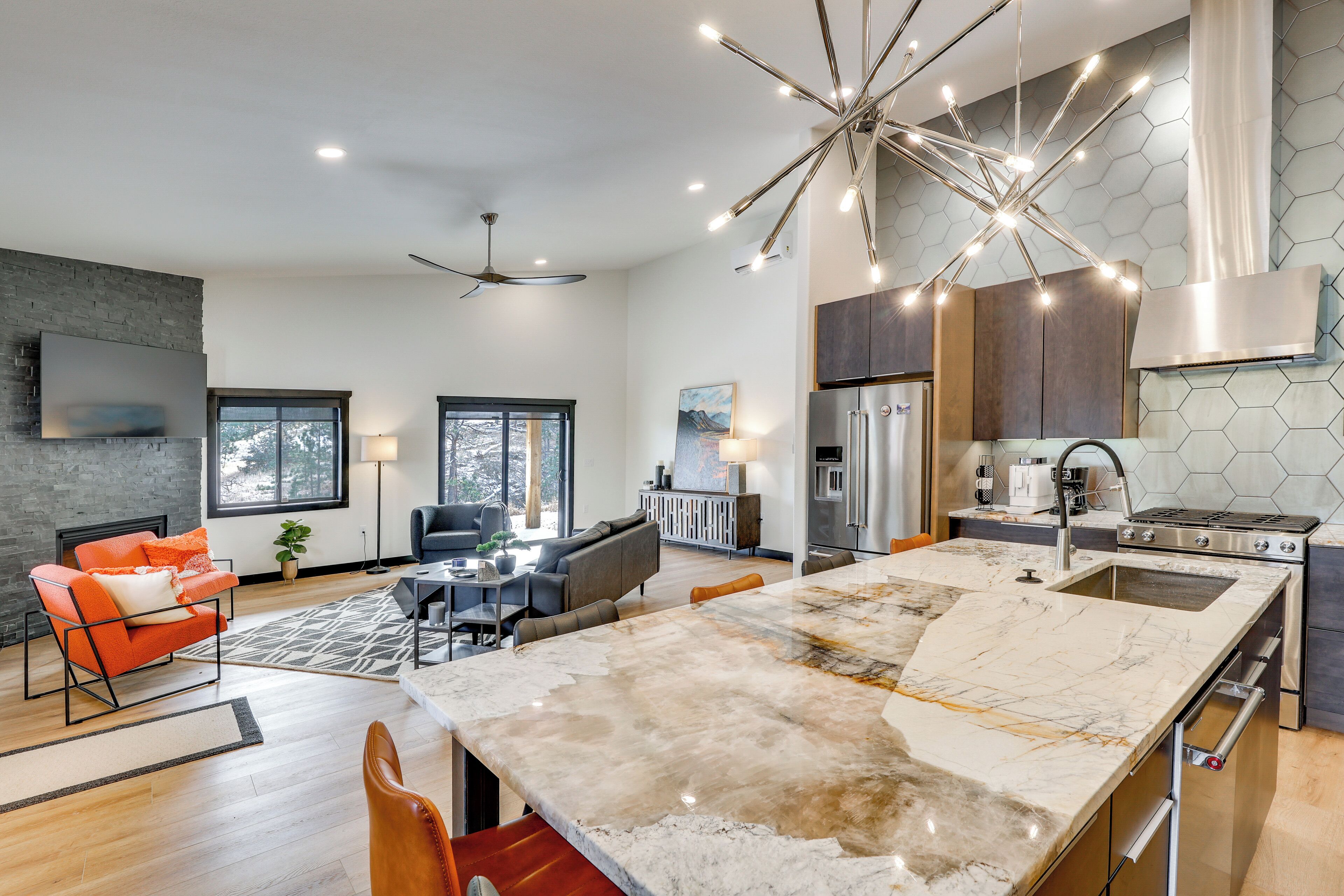 A modern kitchen with a large island, stainless steel appliances, and a unique ceiling light fixture.