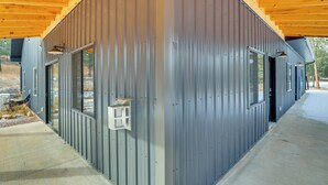 Un bâtiment moderne doté d’une façade métallique, de grandes fenêtres et d’un plafond en bois.